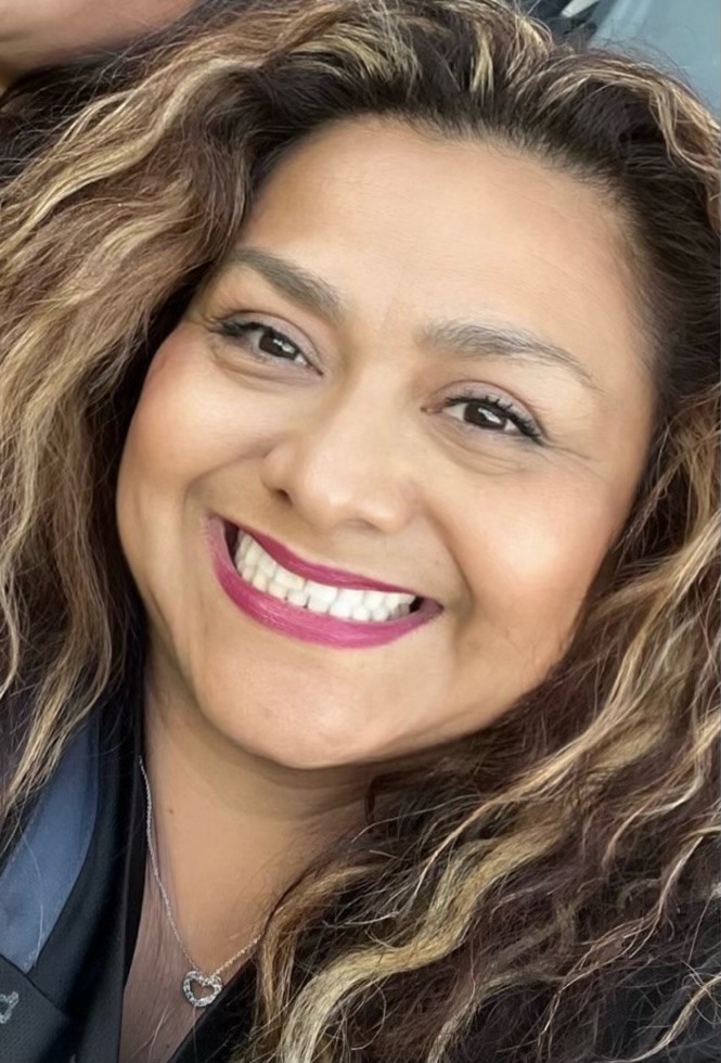 Julissa Castillo, a smiling woman with light brown skin, long brown hair with highlights.